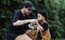 Un padre ayuda a su hijo pequeño a beber agua al aire libre en un día caluroso