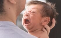 Padre calmando a su bebé con cólico en brazos